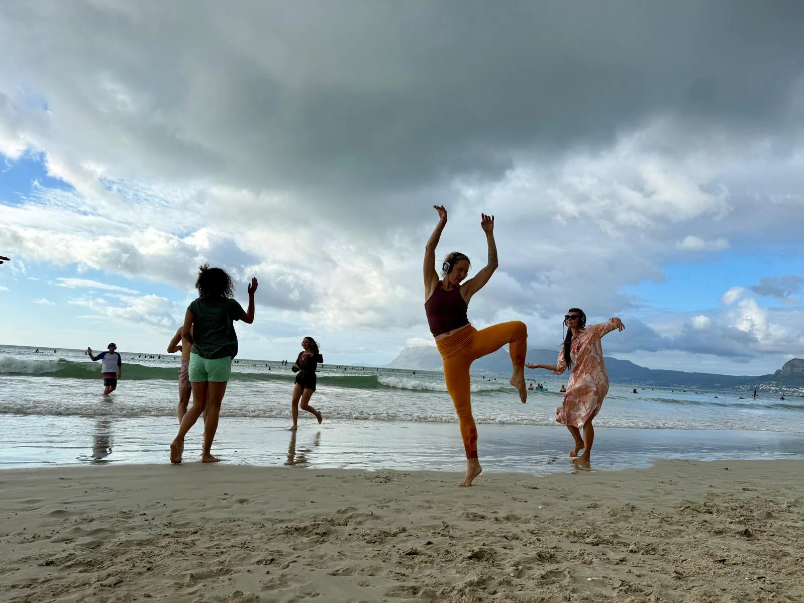 Dancers moving on a beach wearing silent disco headsets at a Body Choir session