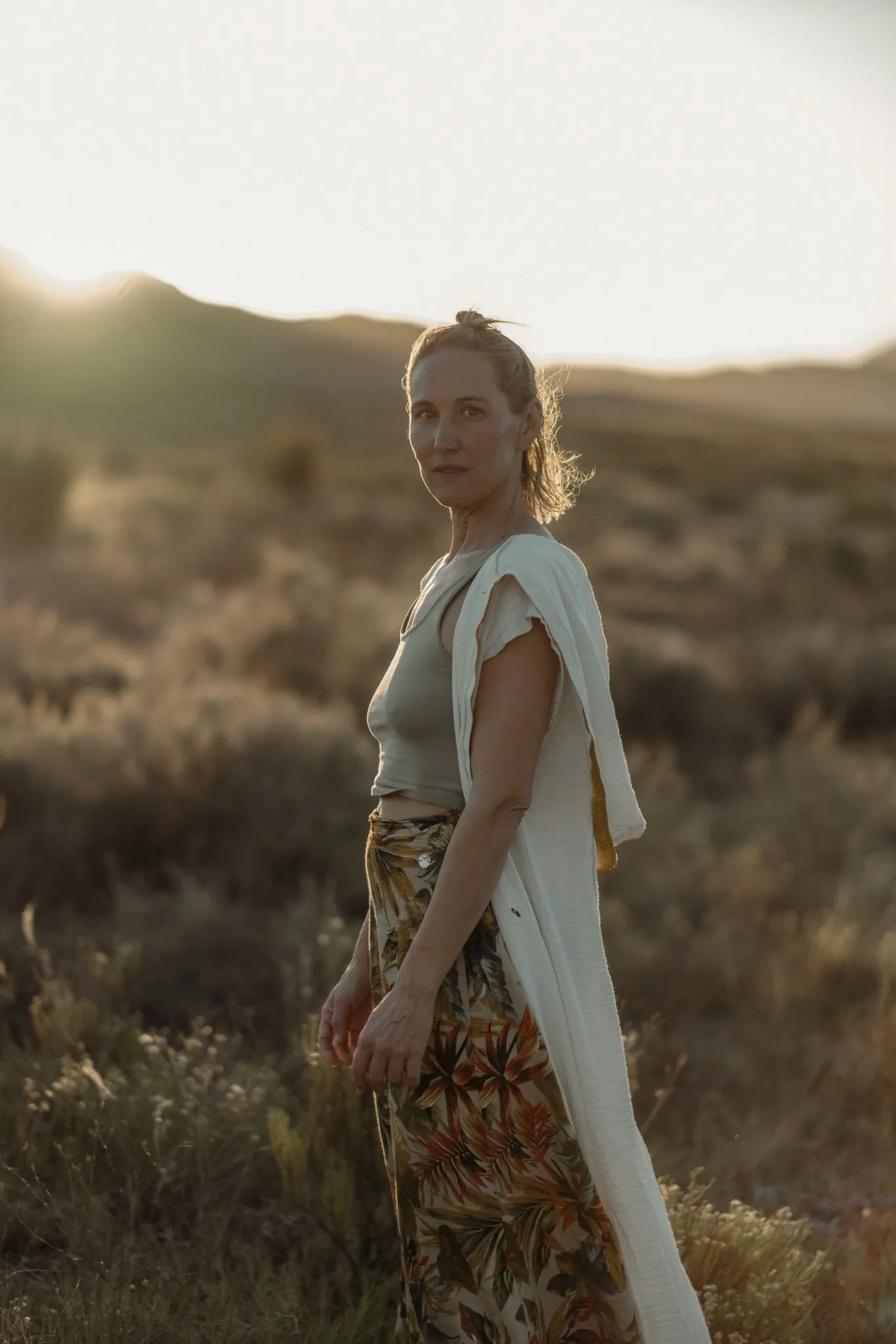 Samantha Claire standing in a wild field at sunset